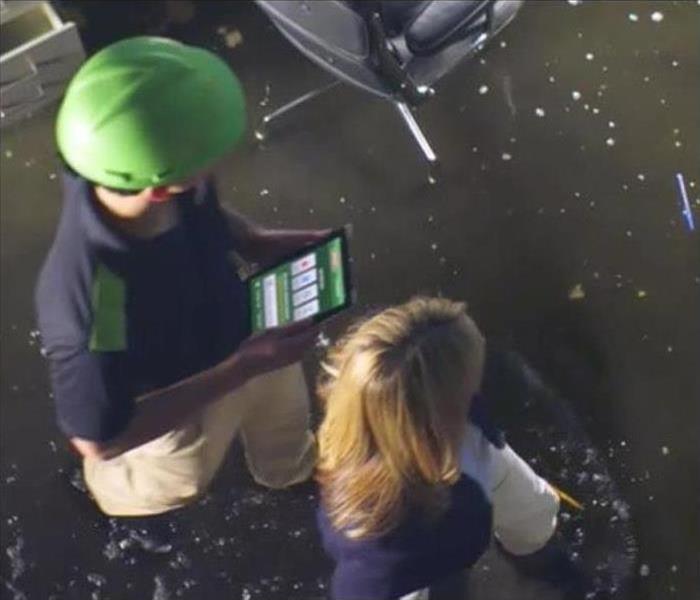 SERVPRO employee and homeowner leaned over iPad.